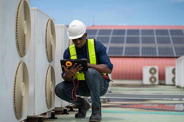 HVAC technician conducting HVAC digital inspections using tablet device for air conditioning system quality control and documentation