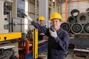 Manufacturing workers in hard hats using digital inspection equipment to prevent manufacturing equipment failures in industrial facility