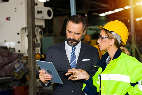 Industrial safety auditor reviewing inspection logs with site manager field eagle